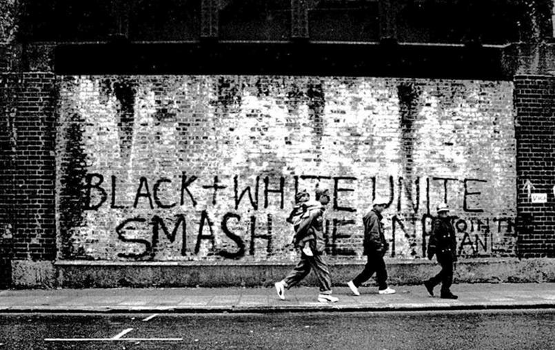 BLACK + WHITE UNITE SMASH THE NF written in graffiti on a wall